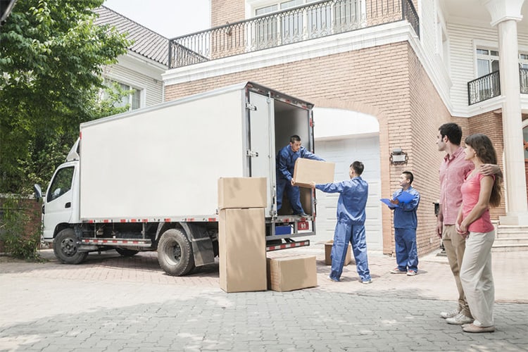 35992731 – young couple watching movers move boxes from the moving van