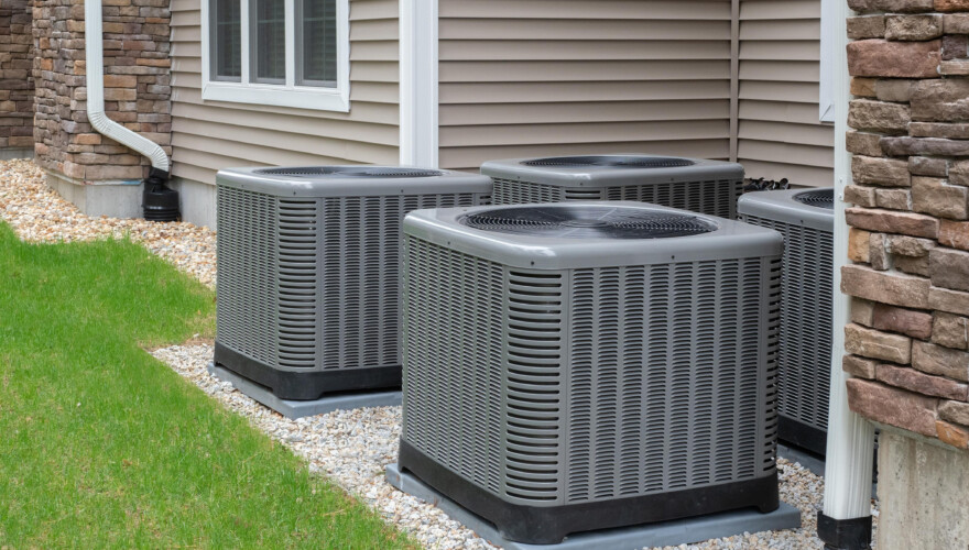 A set of air conditioning units outside a suburban home