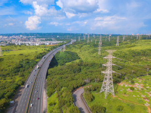 Aerial view of highways and high voltage metal post in the industrial estate. Electricity tower. Top view of green trees in forest landscape in Taichung Downtown, urban city, Taiwan.