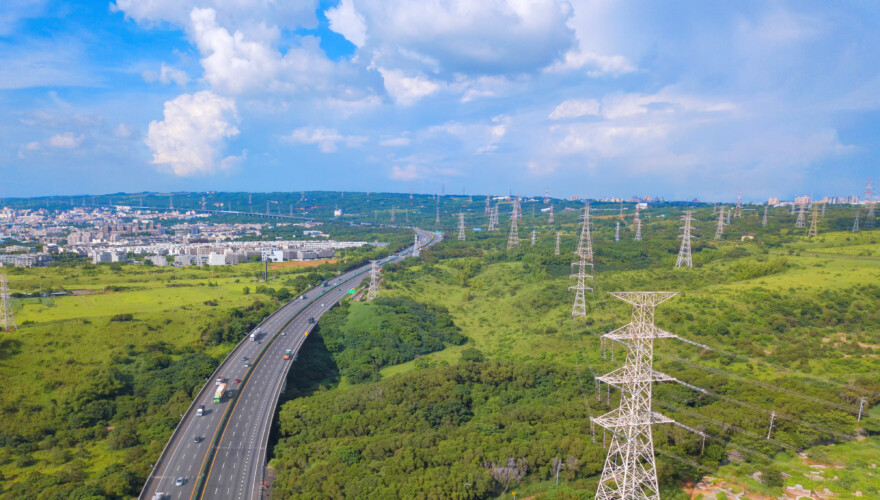 Aerial view of highways and high voltage metal post in the industrial estate. Electricity tower. Top view of green trees in forest landscape in Taichung Downtown, urban city, Taiwan.