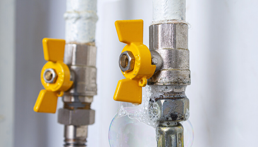 A pair of gas pipes with air bubbles on their surface due to a natural gas leak
