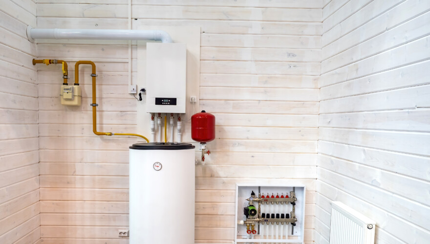 A water heater in a utility room with white, wooden walls