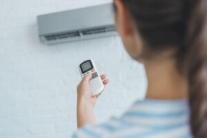 Woman turning on air conditioner with remote control