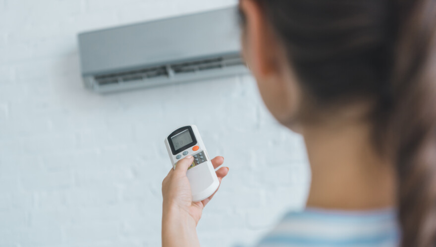 Woman turning on air conditioner with remote control