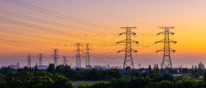 High voltage electricity pylons and transmission lines at sunset.