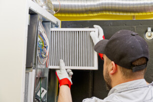 HVAC service technician changing dirty air filter in a central ventilation system.