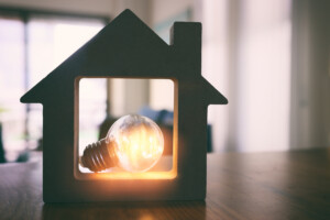 Wood house with Light bulb, resting in a dark home.