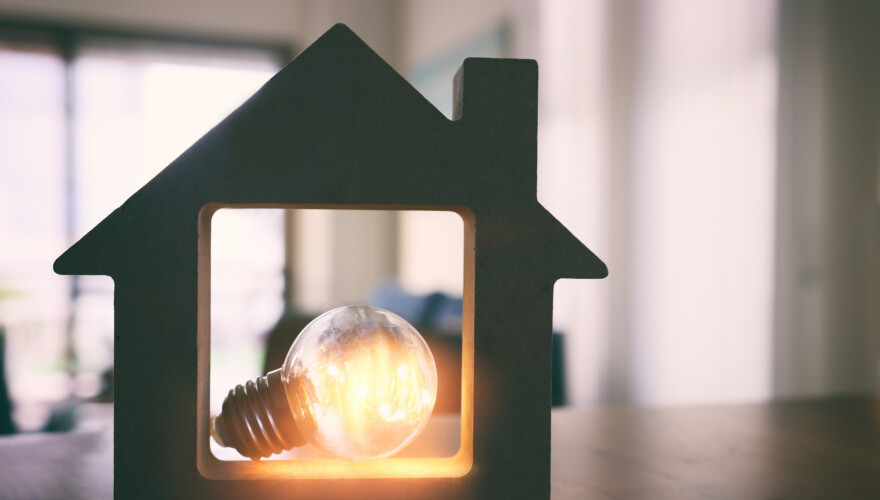 Wood house with Light bulb, resting in a dark home.