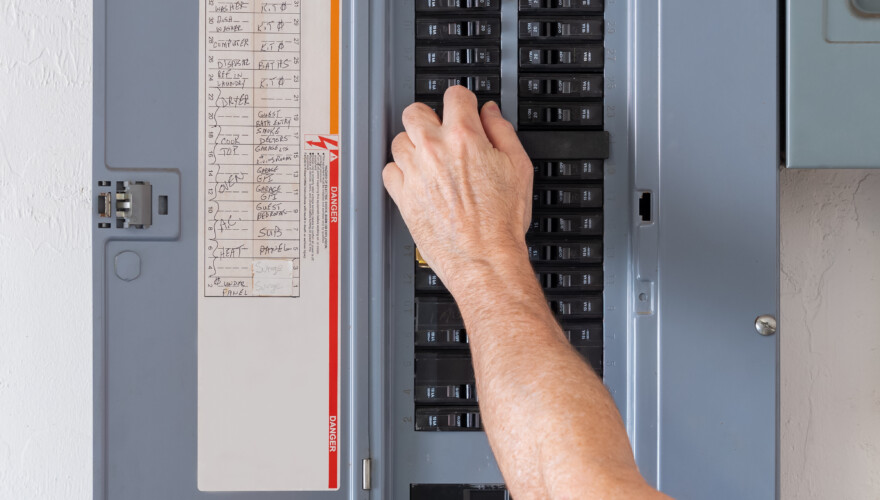 Homeowner resetting tripped breakers on electrical panel